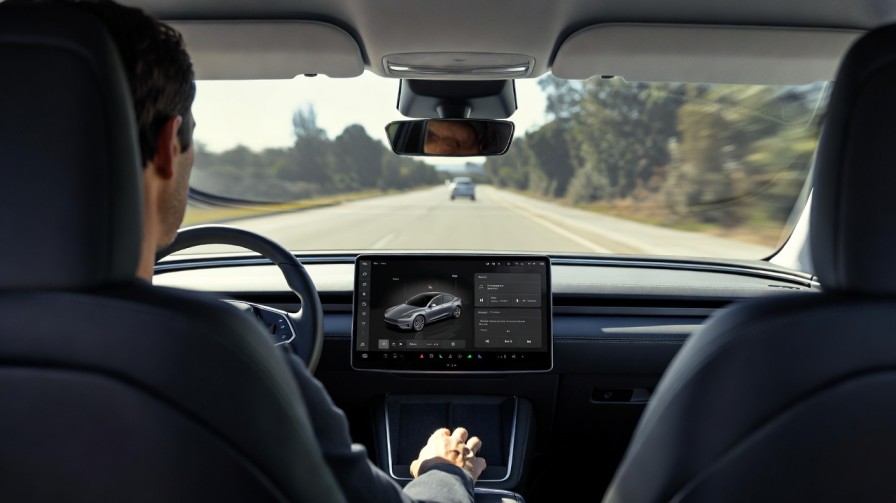 Driver using a car touchscreen while the road is visible ahead, illustrating in-car screen distraction
